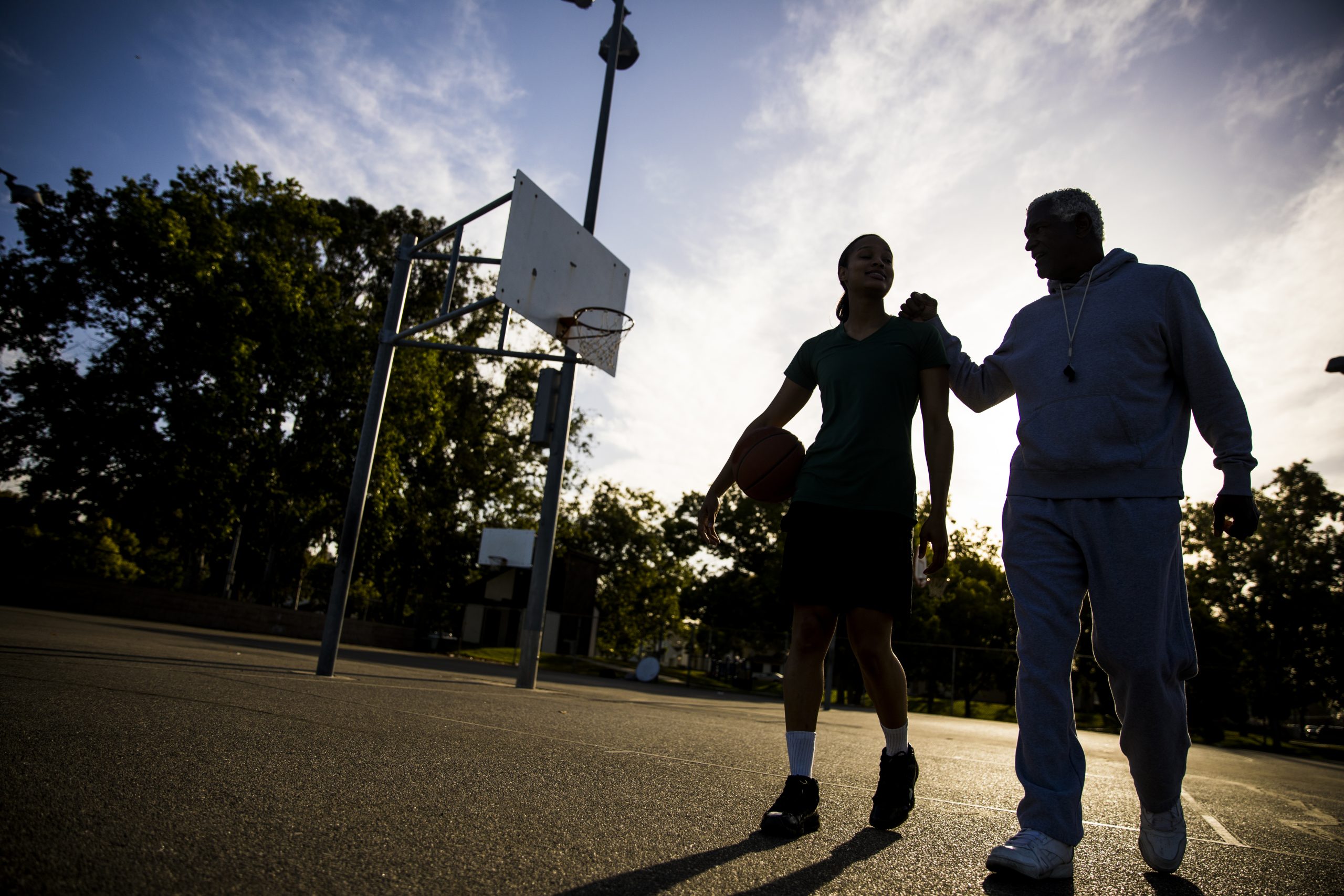 A father and his daughter practice basketball.